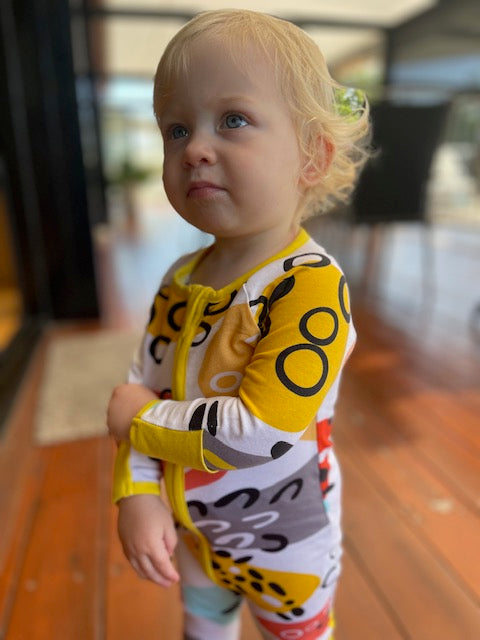 Toddler wearing multi coloured long sleeve baby onesie with fold over hand and foot cuffs
