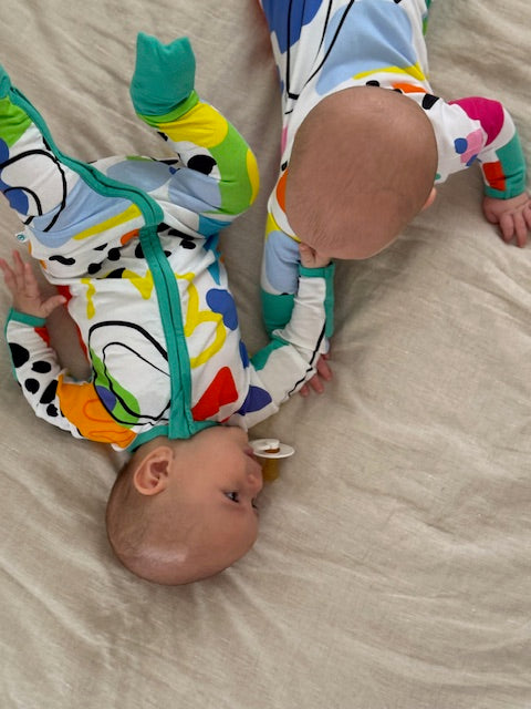 2 babes showing multi coloured long sleeve baby onesie with fold over hand and foot cuffs in unisex design