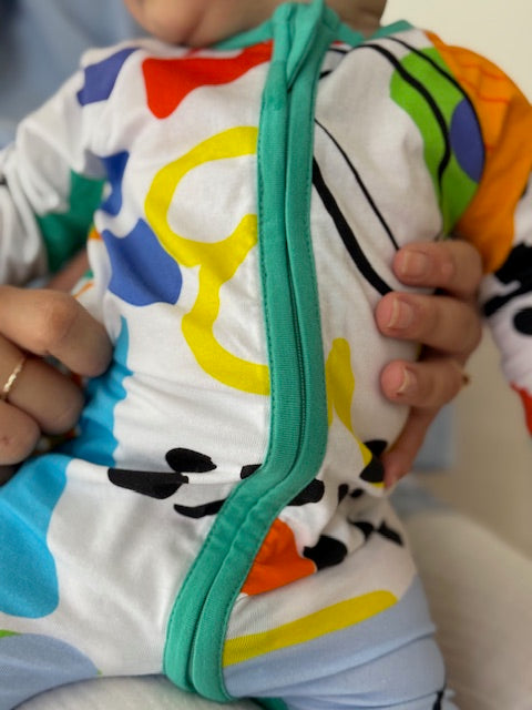 multi coloured long sleeve baby onesie with fold over hand and foot cuffs in unisex design closeup front view
