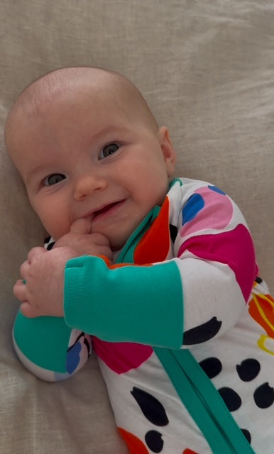 multi coloured long sleeve baby onesie with fold over hand and foot cuffs in unisex design. close up of teal attached hand cuffs