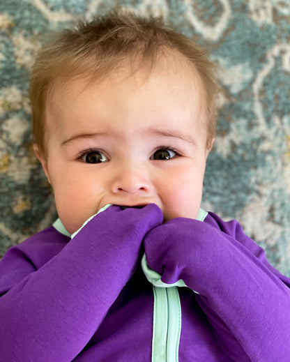 solid purple long sleeve baby onesie with teal trim with fold over hand & foot cuffs and double zip